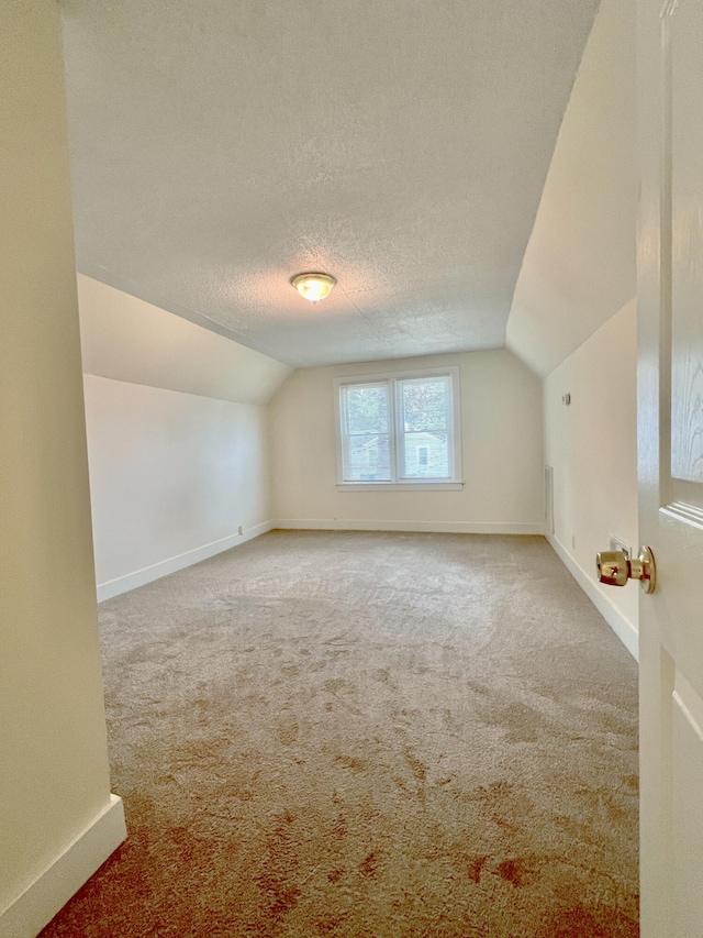 bonus room with lofted ceiling, a textured ceiling, and carpet flooring