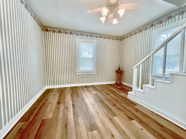 empty room with ceiling fan, hardwood / wood-style flooring, a textured ceiling, and plenty of natural light