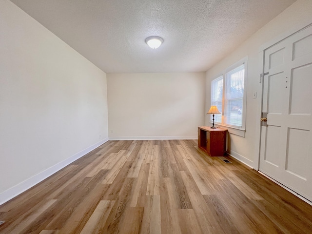 spare room featuring light hardwood / wood-style flooring and a textured ceiling