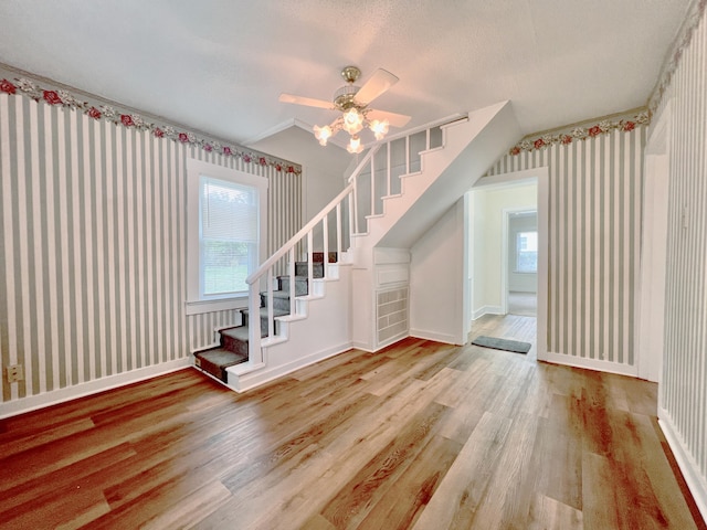 stairs with lofted ceiling, hardwood / wood-style floors, a textured ceiling, and ceiling fan