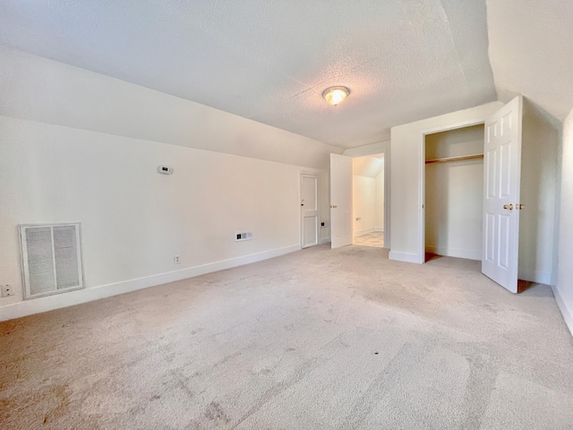 unfurnished bedroom featuring vaulted ceiling, a textured ceiling, and carpet floors