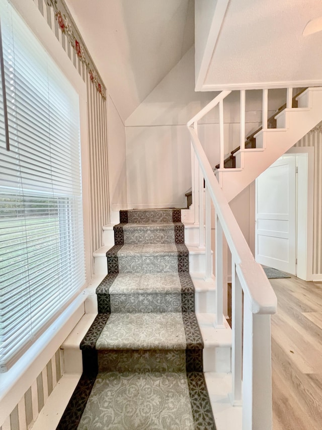 stairway featuring vaulted ceiling and hardwood / wood-style flooring