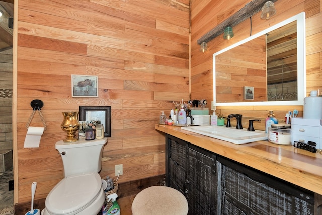 bathroom with vanity, toilet, and wood walls