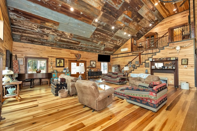 living room with beam ceiling, high vaulted ceiling, wood-type flooring, and wooden walls