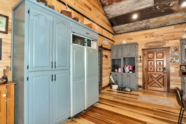 interior space featuring wood walls, hardwood / wood-style flooring, and vaulted ceiling