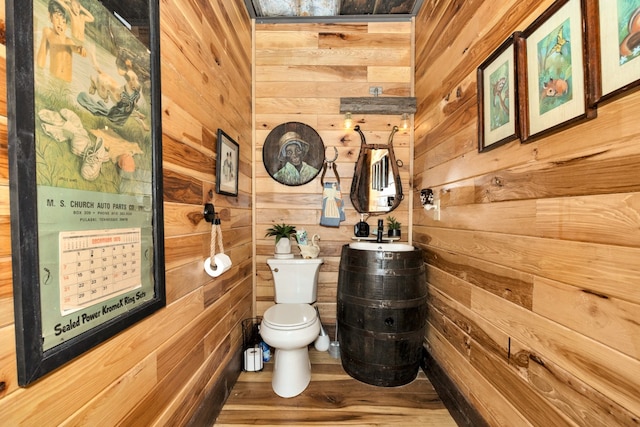 bathroom with toilet, hardwood / wood-style flooring, and wooden walls