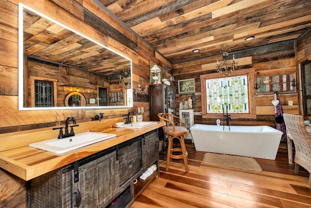 bathroom with wood walls, a washtub, wooden ceiling, vanity, and hardwood / wood-style flooring