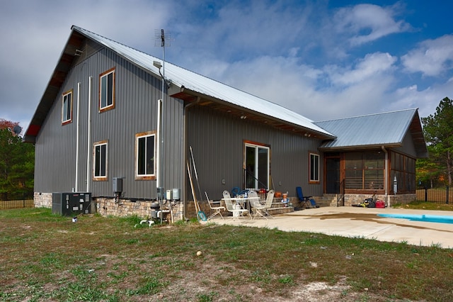 rear view of property with a sunroom, a covered pool, and a patio area