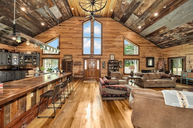 living room featuring light hardwood / wood-style floors, wood walls, high vaulted ceiling, and wooden ceiling