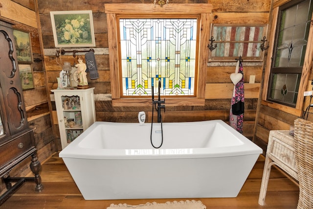 bathroom featuring a tub, hardwood / wood-style flooring, and wooden walls