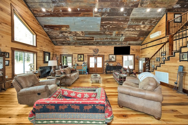 living room with wood walls, hardwood / wood-style floors, and french doors