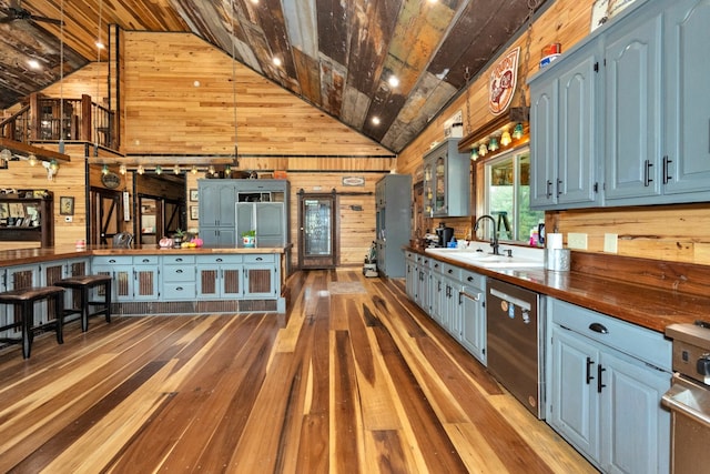 kitchen with hardwood / wood-style flooring, wooden walls, wood counters, sink, and appliances with stainless steel finishes