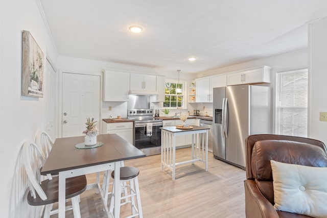 kitchen with backsplash, white cabinetry, pendant lighting, light hardwood / wood-style floors, and stainless steel appliances