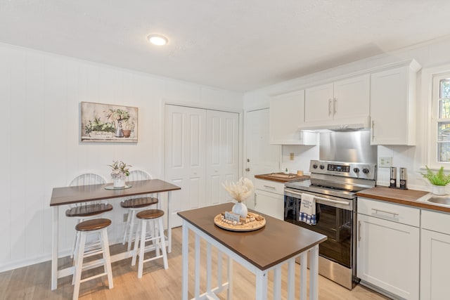 kitchen featuring white cabinets, wood counters, a textured ceiling, stainless steel electric range oven, and light hardwood / wood-style floors