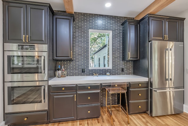 kitchen with beam ceiling, decorative backsplash, stainless steel appliances, and light wood-type flooring