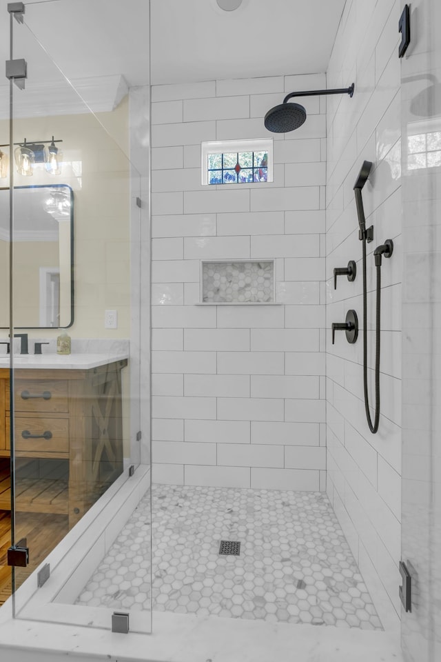 bathroom with vanity, tiled shower, and ornamental molding