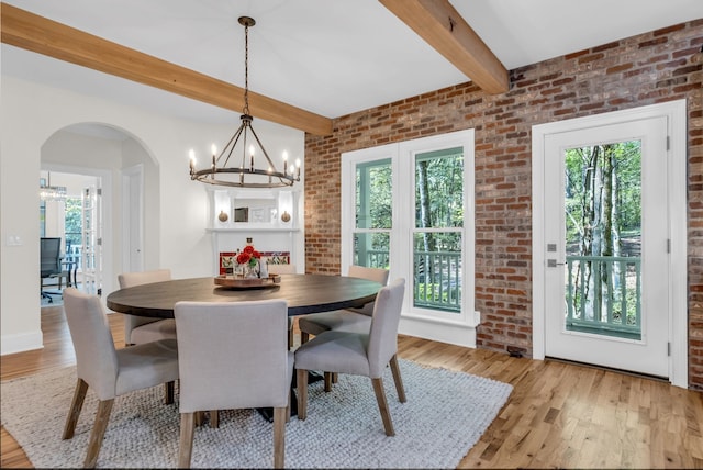 dining area with light hardwood / wood-style floors, brick wall, and plenty of natural light