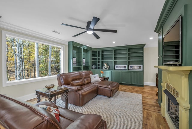 living room featuring crown molding, light wood-type flooring, and ceiling fan