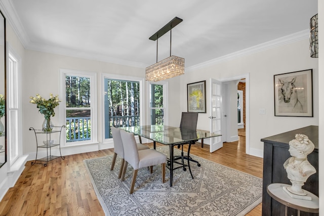 dining space featuring a notable chandelier, light hardwood / wood-style floors, and crown molding