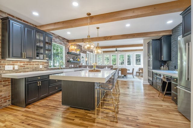 kitchen with a kitchen island, a breakfast bar area, light hardwood / wood-style flooring, pendant lighting, and stainless steel refrigerator