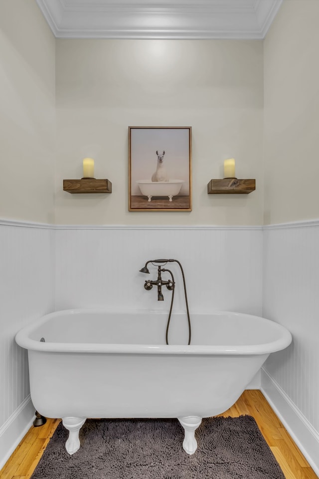 bathroom with crown molding, wood-type flooring, and a tub to relax in