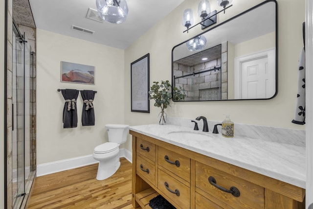 bathroom with toilet, hardwood / wood-style flooring, vanity, and a shower with door