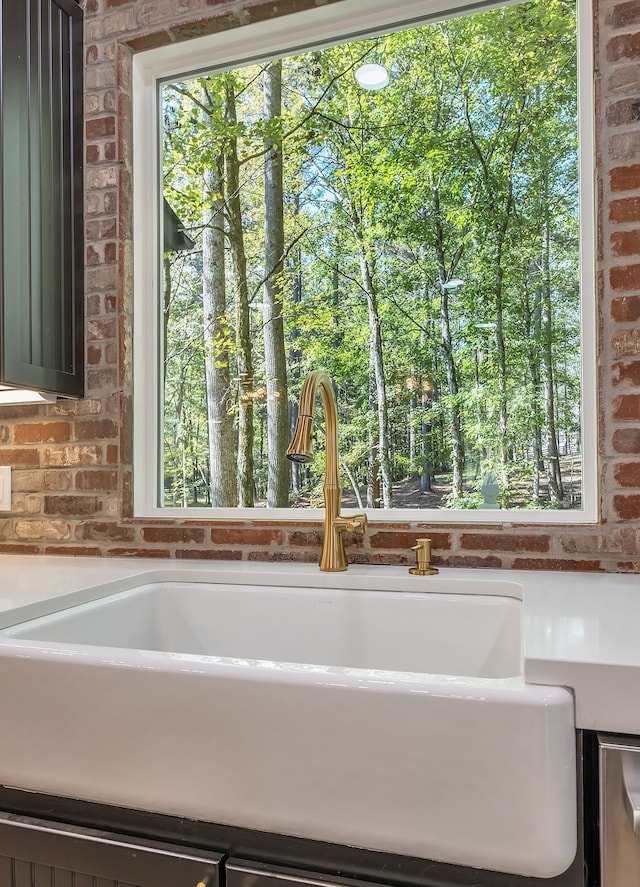 bathroom with a healthy amount of sunlight, sink, and brick wall