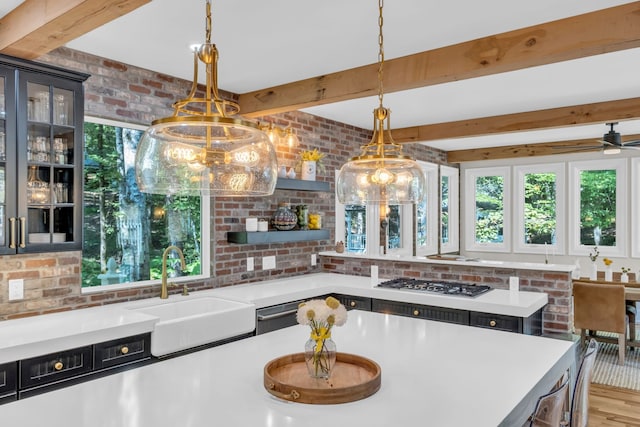 kitchen featuring brick wall, sink, hanging light fixtures, and light hardwood / wood-style floors