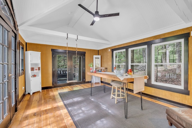 dining room with wooden walls, lofted ceiling with beams, light wood-type flooring, and ceiling fan