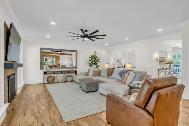 living room with light hardwood / wood-style flooring, ornamental molding, and ceiling fan