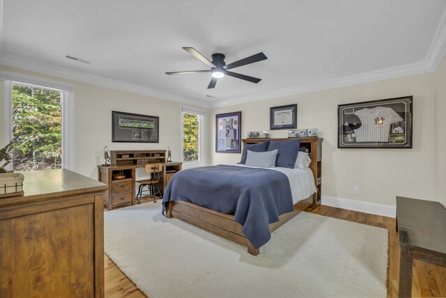 bedroom with light hardwood / wood-style flooring, ornamental molding, and ceiling fan