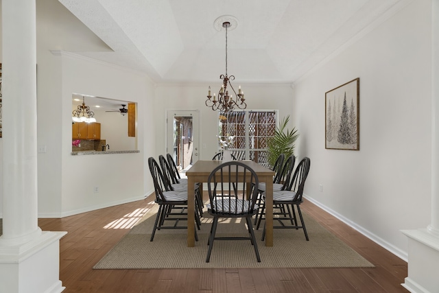 dining space featuring decorative columns, hardwood / wood-style flooring, and ceiling fan with notable chandelier