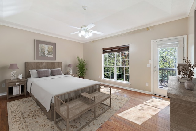 bedroom with ceiling fan, a tray ceiling, access to outside, and light hardwood / wood-style flooring