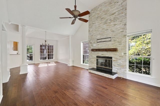 unfurnished living room with decorative columns, ceiling fan with notable chandelier, high vaulted ceiling, and dark hardwood / wood-style flooring