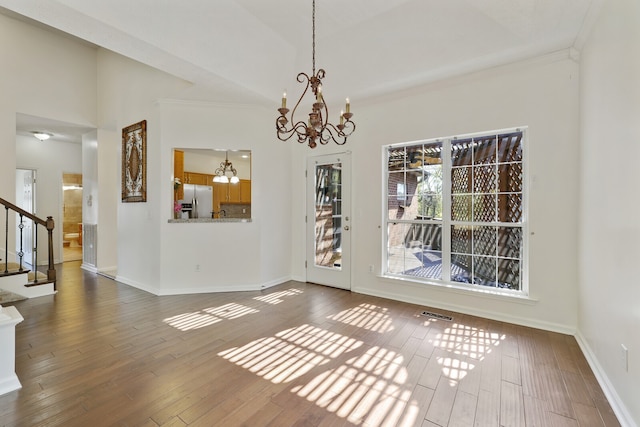 unfurnished dining area featuring hardwood / wood-style floors, crown molding, and ceiling fan with notable chandelier