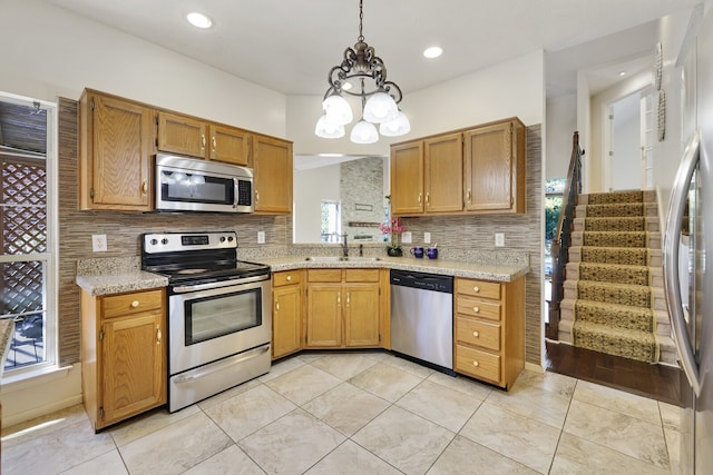 kitchen featuring appliances with stainless steel finishes, a chandelier, pendant lighting, and a wealth of natural light