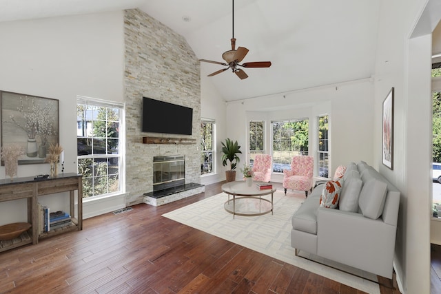 living room featuring a stone fireplace, hardwood / wood-style floors, a healthy amount of sunlight, and high vaulted ceiling