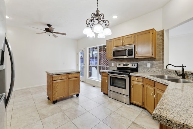 kitchen with sink, a kitchen island, stainless steel appliances, decorative light fixtures, and decorative backsplash