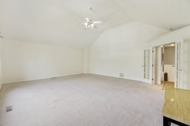 additional living space with lofted ceiling, french doors, light colored carpet, and ceiling fan