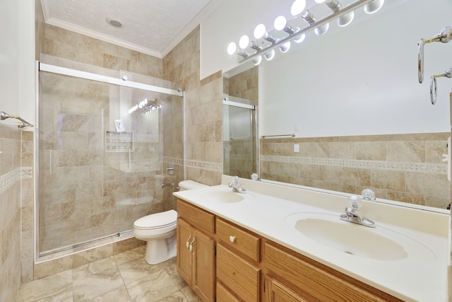 bathroom featuring a shower with door, toilet, ornamental molding, tile walls, and vanity