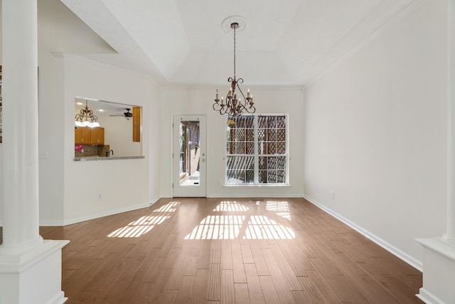 unfurnished dining area with ornate columns, hardwood / wood-style flooring, crown molding, and ceiling fan with notable chandelier