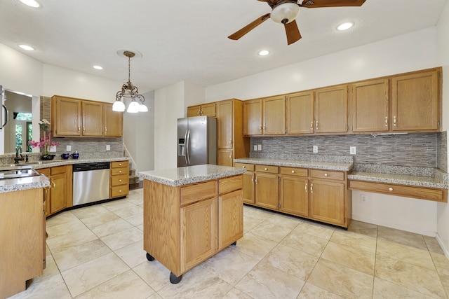 kitchen featuring ceiling fan with notable chandelier, a center island, hanging light fixtures, stainless steel appliances, and decorative backsplash