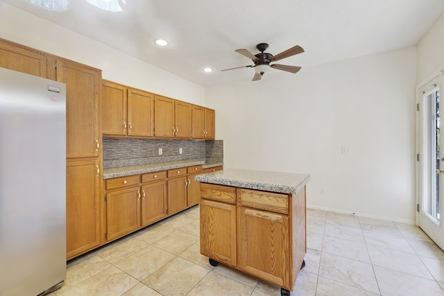 kitchen with decorative backsplash, stainless steel fridge, a center island, light tile patterned flooring, and ceiling fan