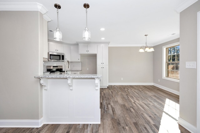 kitchen featuring pendant lighting, light wood-type flooring, white cabinetry, appliances with stainless steel finishes, and light stone counters