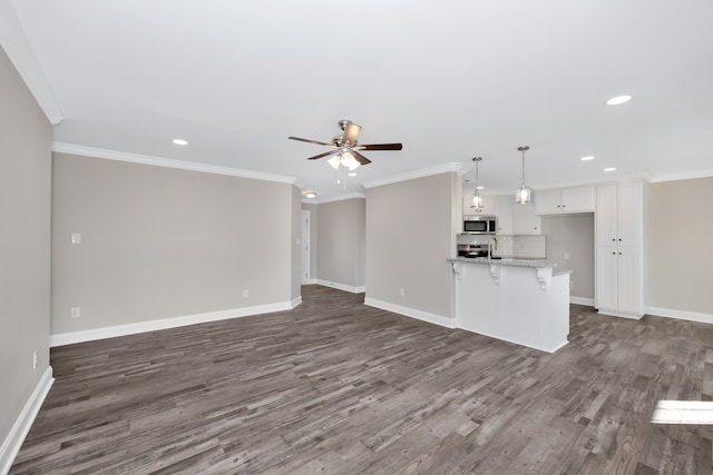 unfurnished living room featuring ornamental molding, dark hardwood / wood-style floors, and ceiling fan