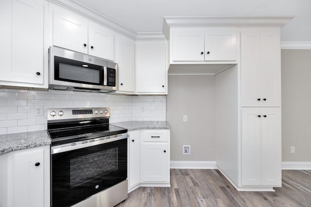 kitchen with white cabinetry, stainless steel appliances, and light stone countertops