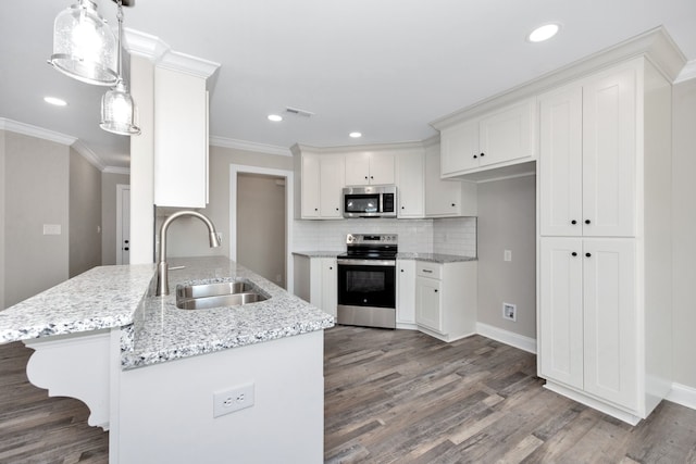 kitchen with sink, hanging light fixtures, stainless steel appliances, white cabinets, and hardwood / wood-style flooring