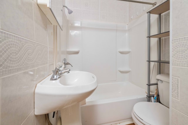 bathroom with toilet, tile walls, and washtub / shower combination