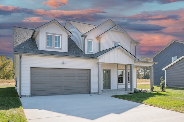 view of front of house with a porch, a yard, and a garage