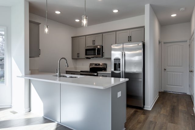 kitchen featuring dark wood-type flooring, sink, hanging light fixtures, appliances with stainless steel finishes, and kitchen peninsula